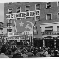 Anni Cinquanta, manifestazione elettorale del PCI, in Piazza Matteotti, Modena. I manifesti coprono la facciata della libreria Rinascita, il cui ingresso era sotto al portico
[ISMO, APCMO]