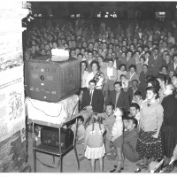 6 settembre 1956, il pubblico assiste alla trasmissione Lascia o raddoppia? Durante la serata conclusiva dell’undicesima edizione della Festa de l’Unità di Modena. Il successo della trasmissione era tale che per assicurarsi una buona presenza di pubblico gli organizzatori della festa installarono dei televisori “a schermo panoramico” per mandare in onda il gioco televisivo durante l’ultima serata. 
[ISMO, AFPCMO]