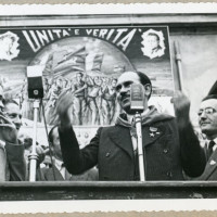 Walter Audisio, “Colonnello Valerio”, parla al pubblico a Reggio Emilia nel 1947. Alla sua sinistra Didimo Ferrari “Eros” e alle sue spalle un cartellone di propaganda de L'Unità